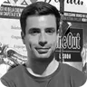 Man smiling, short dark hair, postered background.